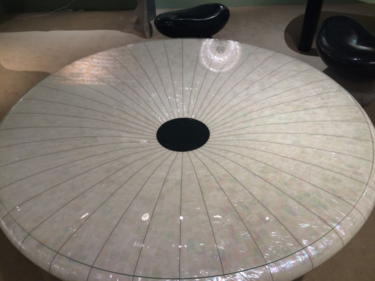 Her "From the Glitter" Table sloped inward toward the center and is topped with glass.