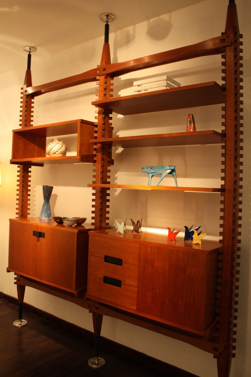 This shelf is simple and clean, but still incorporates amazing wood detail work along the vertical lines. Thanks to the tension posts, it is spare, standing on three single legs.