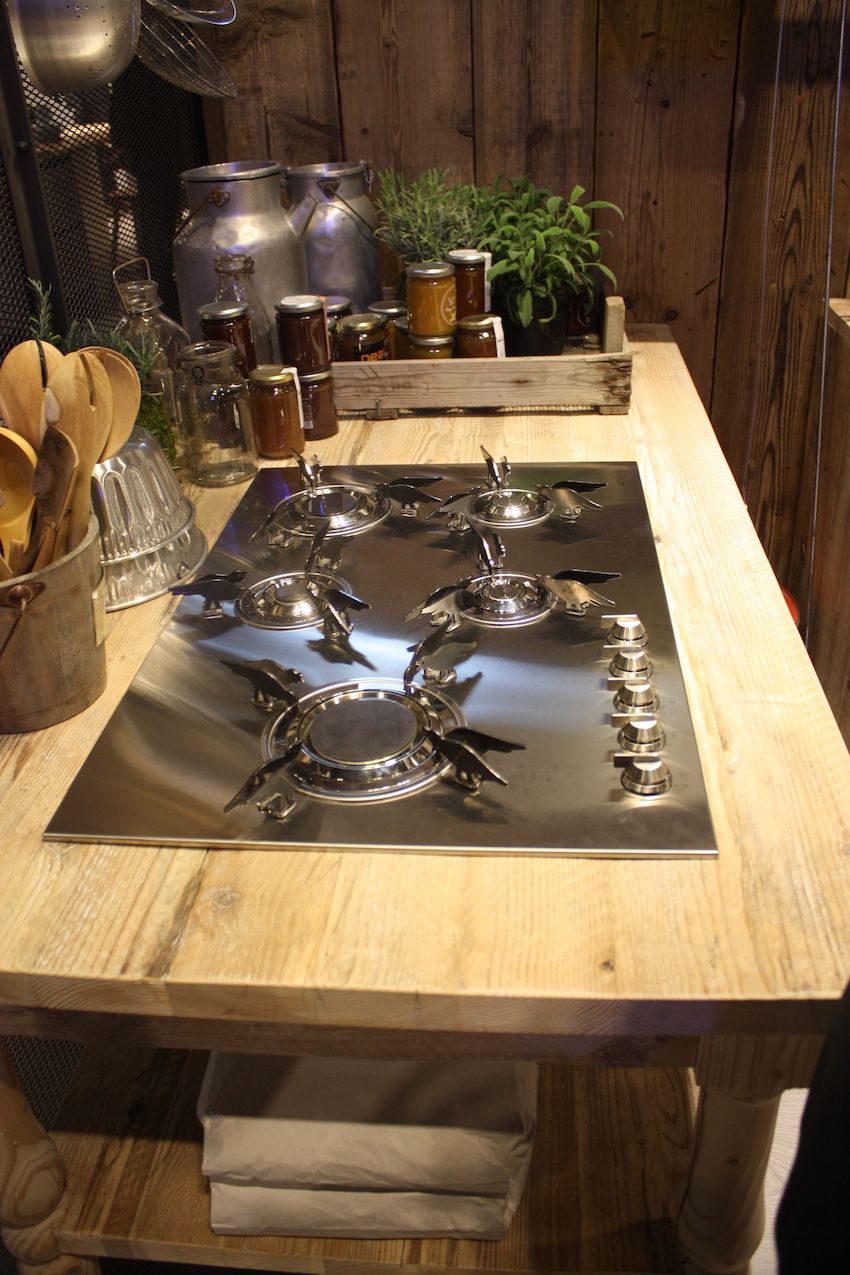 A shiny, modern, state-of-the-art gas cooktop from Smeg is combined with a rustic butcher block island in this Stosa kitchen. By carefully incorporating modern elements, the kitchen can still achieve a rustic, farmhouse feel.