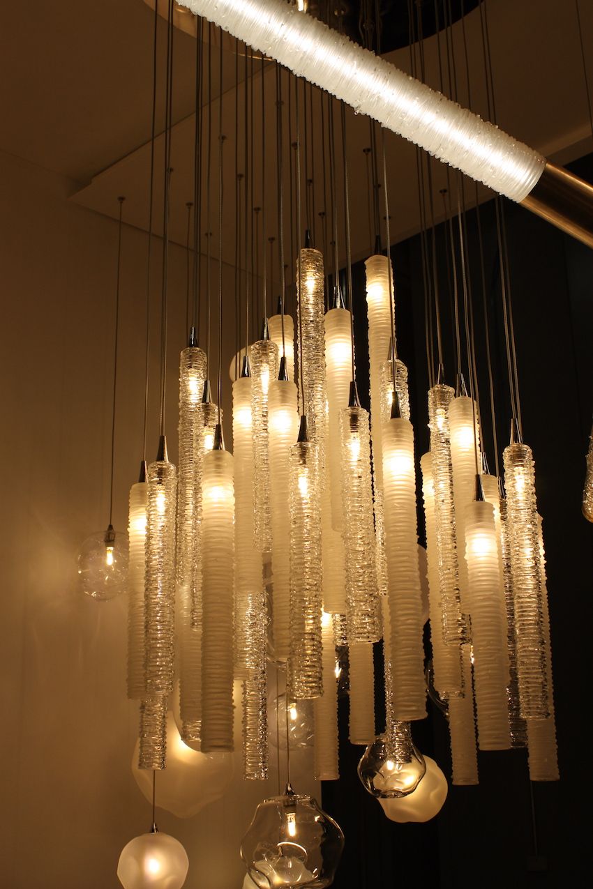 Rows and rows of cylinders of molten glass coils make up this Tamar suspension chandelier. The soft light emitted from these tubes softly illuminates the artful glass work.