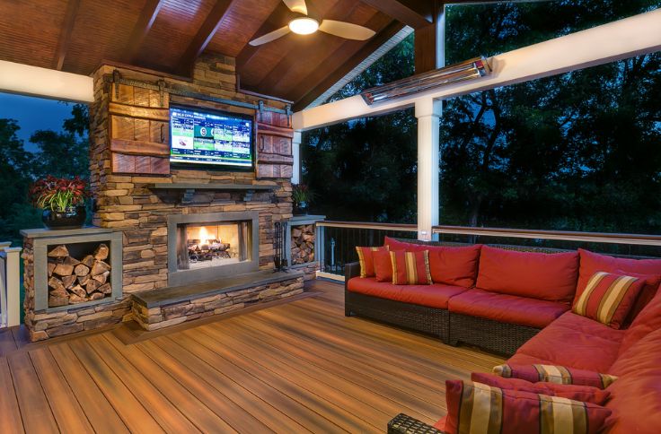 Stone outdoor fireplace with barn doors to hide tv and deck on floor