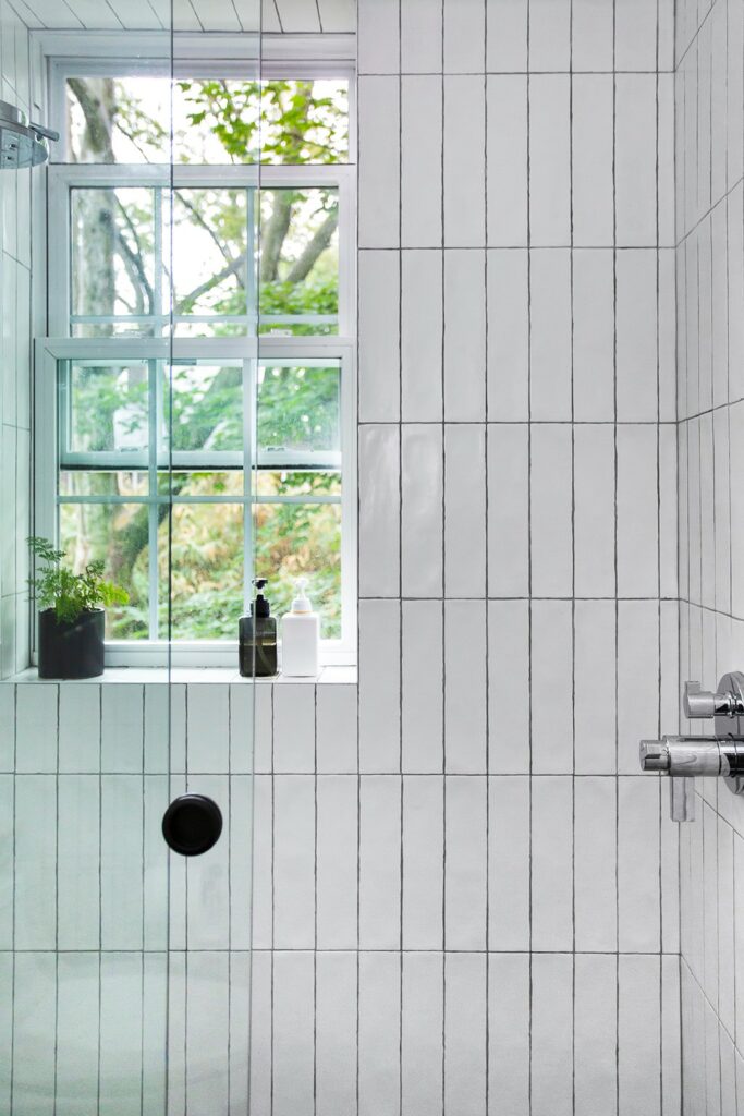 Glass enclosed shower with vertically stacked subway tile