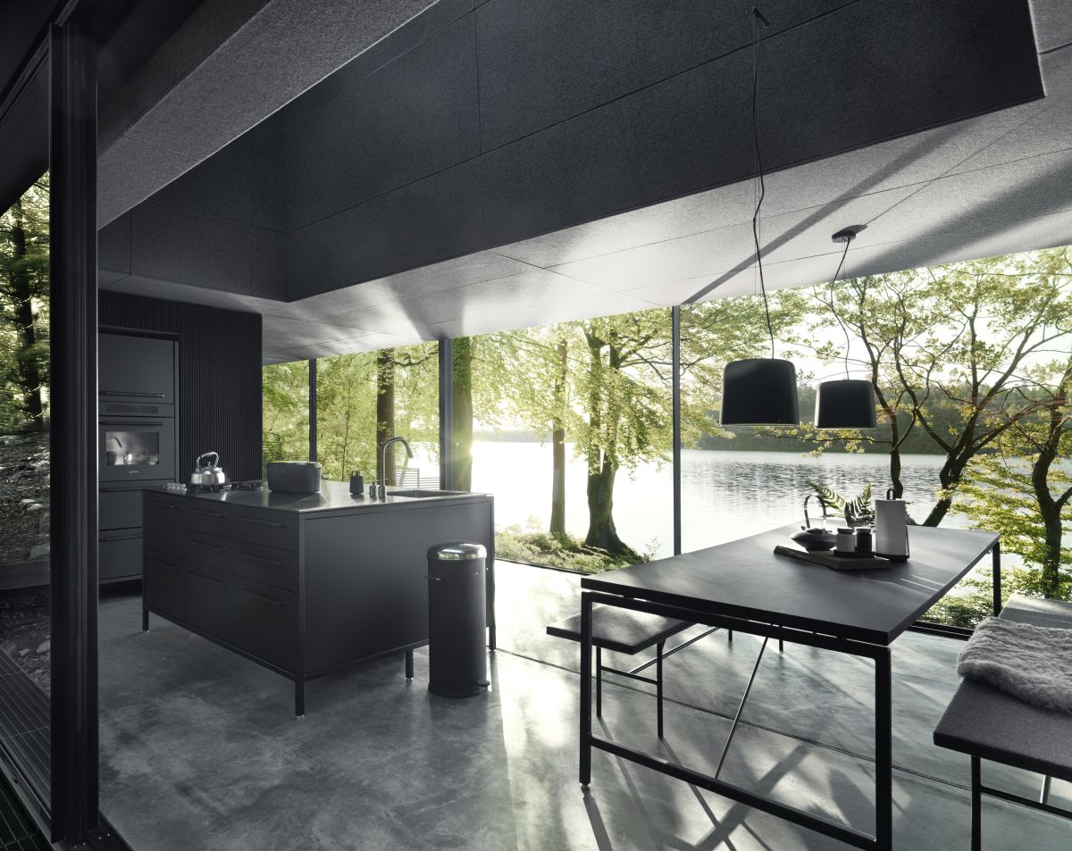 The kitchen, dining space and living area are all part of an open floor plan with glazed walls and concrete flooring