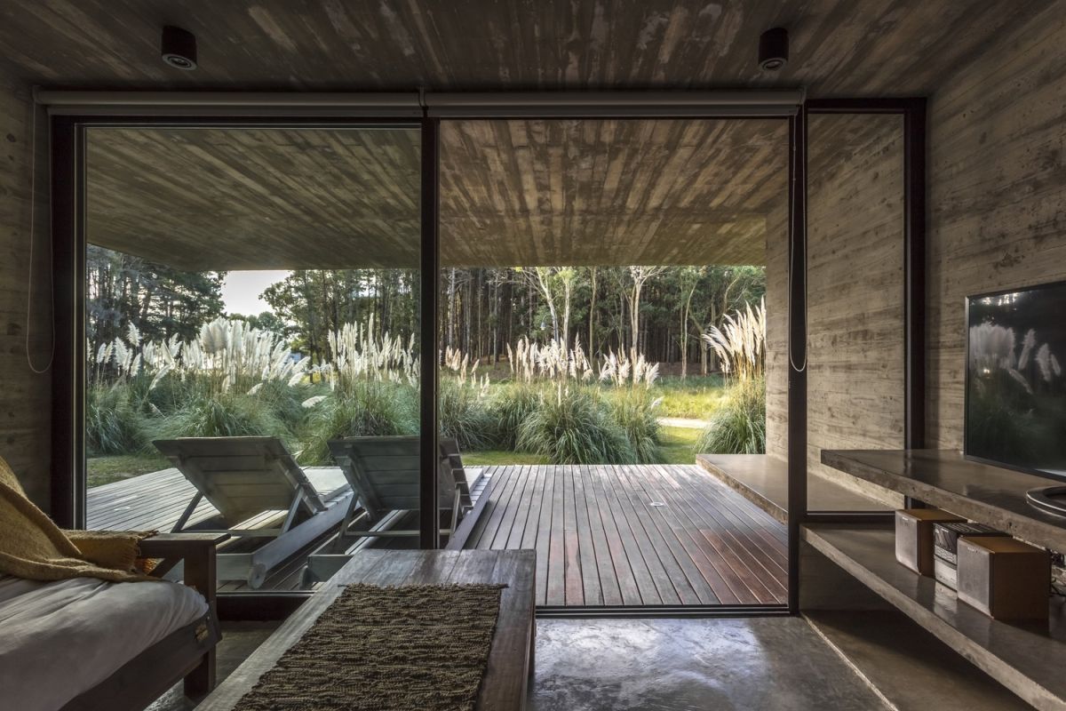 The living area seamlessly extends outdoors, featuring a sliding glass door to a large, covered deck