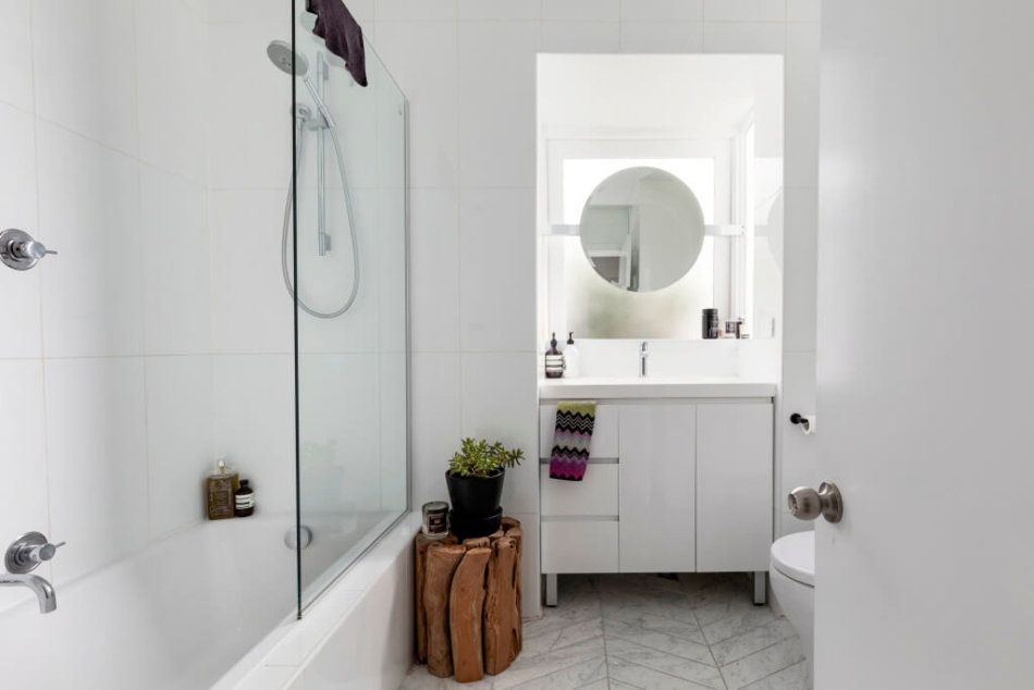 White bathroom with glass shower doors and sky lighting