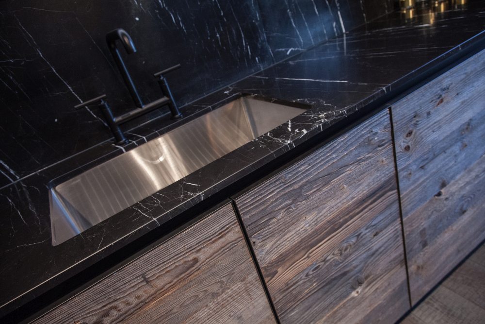 Modern kitchen design featuring black marble and unfinished wood for doors two different materials