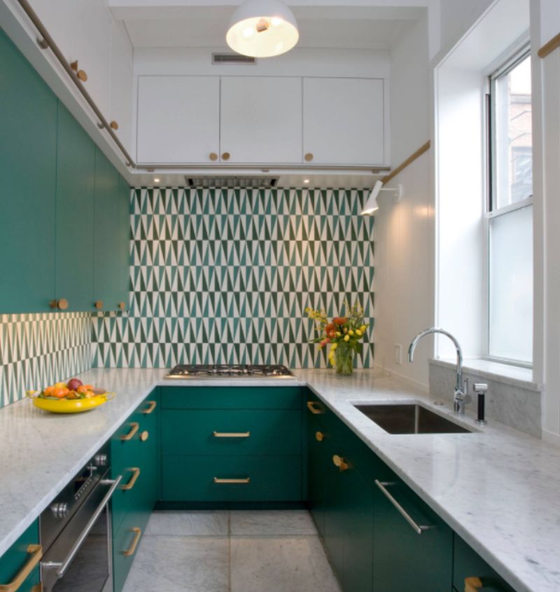 Kitchen with white marble countertops and green cabinets and multicolored backsplash