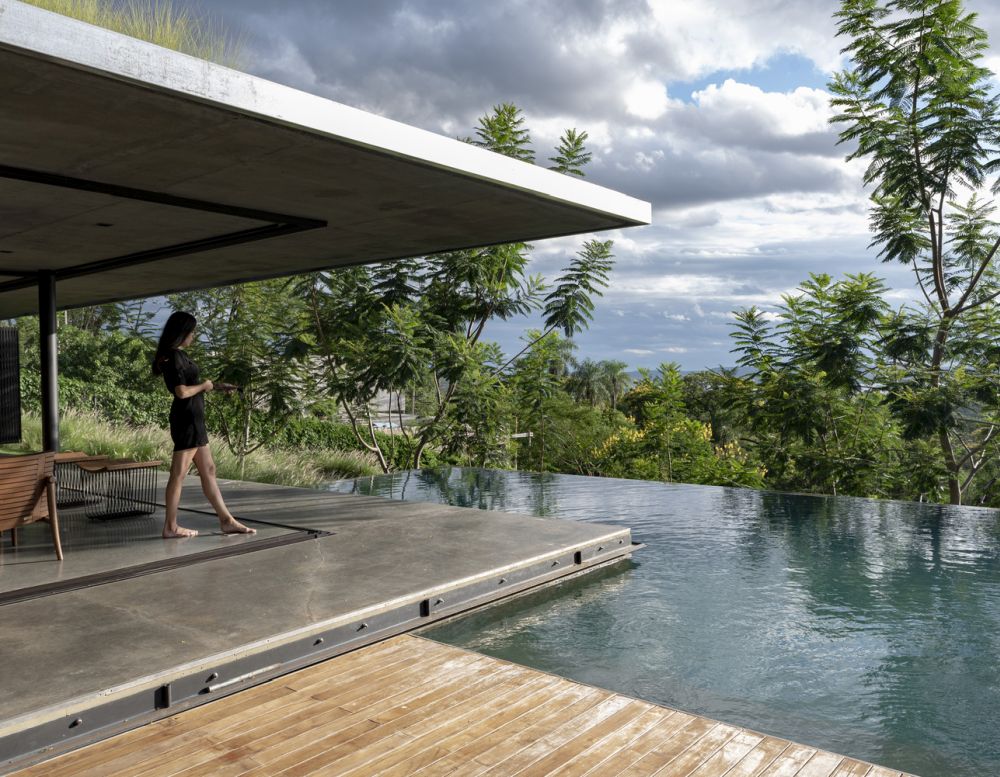 The polished concrete floor extends towards the pool area, creating a small terrace around the house