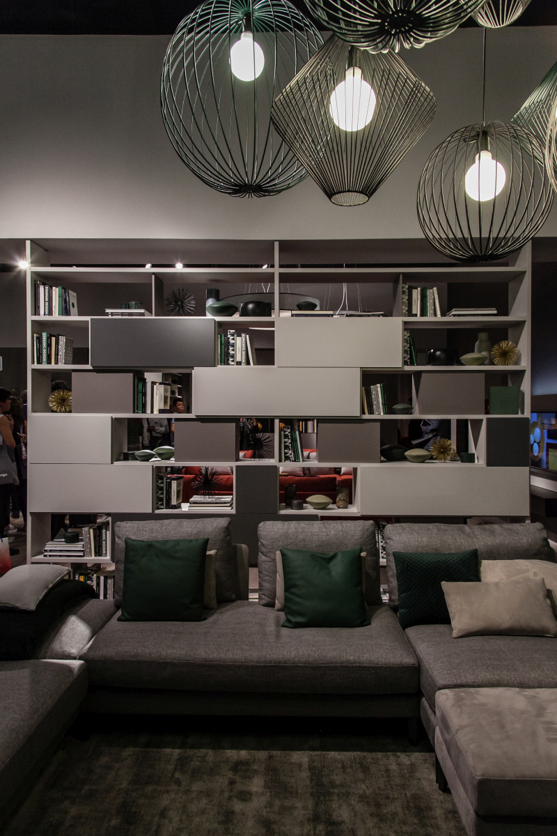 Open shelves and closed cabinets form a screen behind the sofa