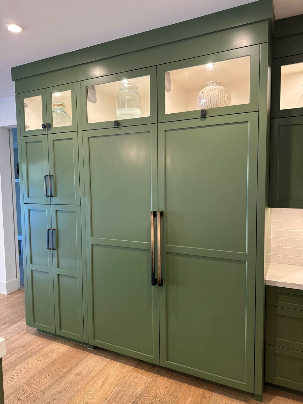 The Refrigerator Disappears Behind Green Cabinet Panels
